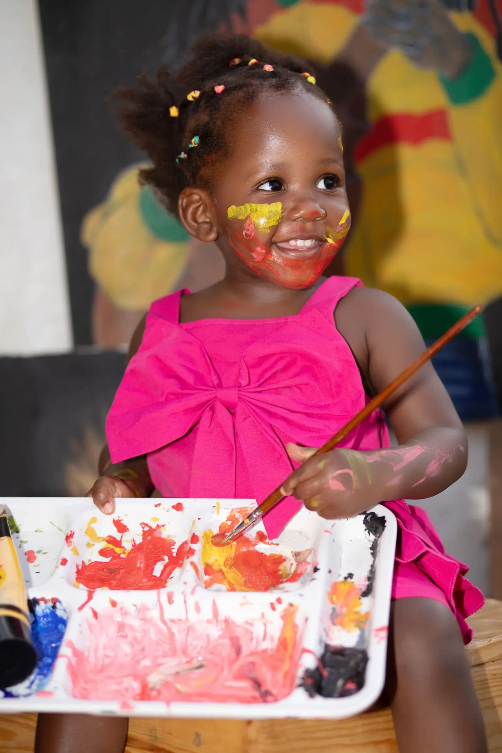 Happy child with a paintbrush and paint on her face