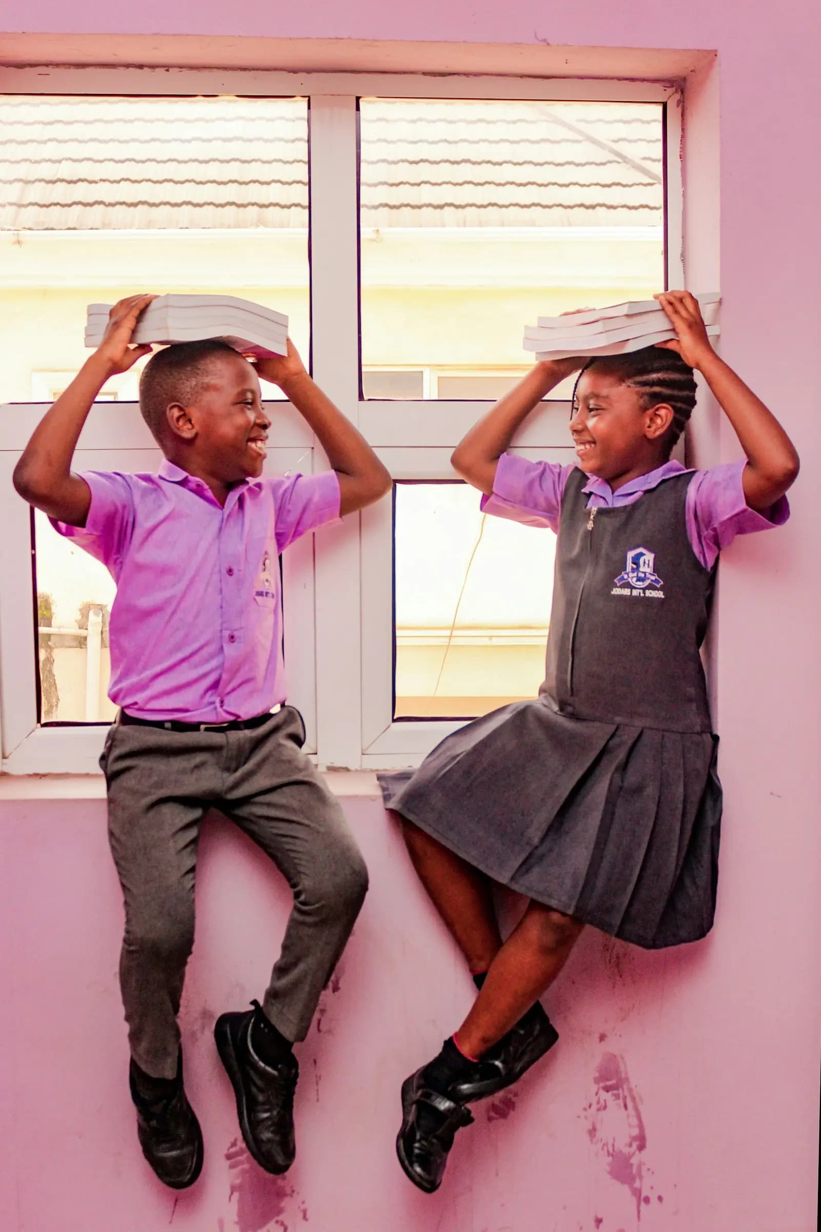 Two smiling pupils in uniform by the classroom window